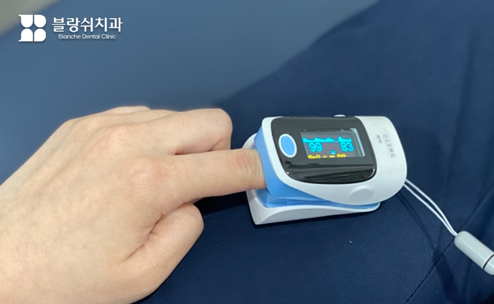 안전한 수면 치료 치과 진료를 위해 환자의 손가락에 산소포화도 측정 장치를 부착하고 실시간으로 건강 상태를 체크하는 장면
