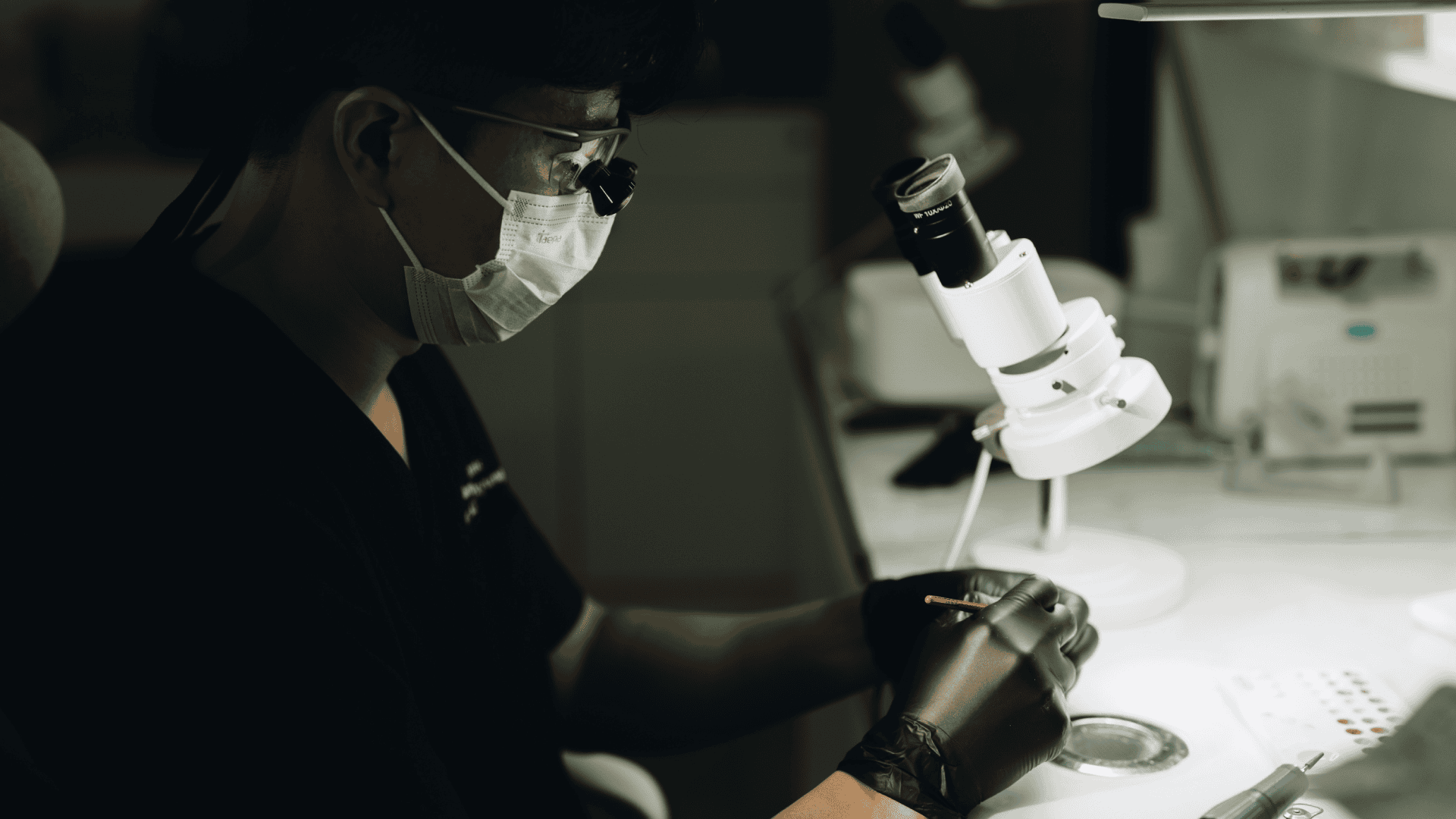 Veneer Fabrication at Blanche Lab Dental laboratory technician working at a bench beside a microscope.